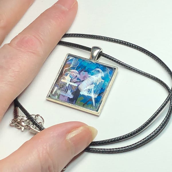 Square chunky pendant featuring two holographic birdcages