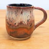 Large stoneware pottery mug finished in multi-coloured purple and copper glaze.