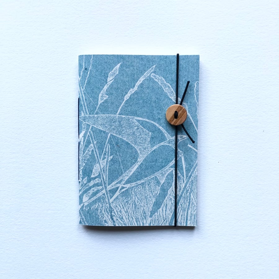 Notebook. Pocket sized. Swallow over grassland.