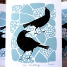 A lino cut greetings card of two blackbirds flirting on the crazy paving