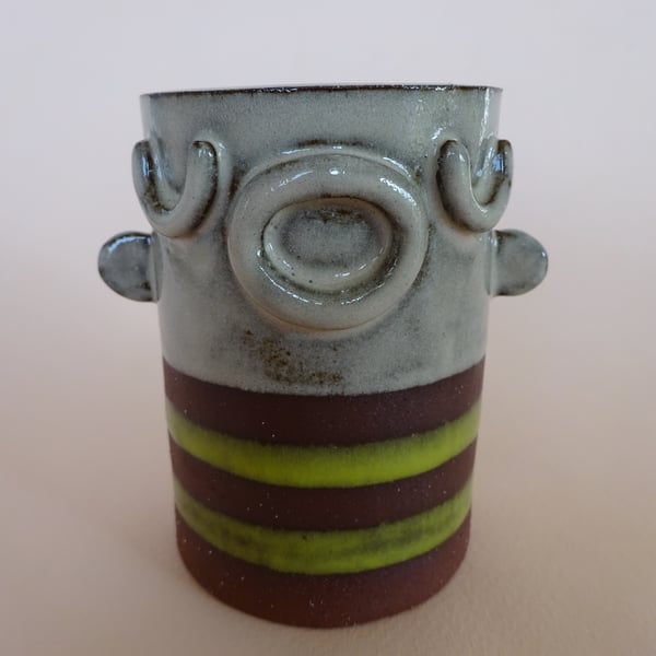 Ceramic face pot with closed eyes, sticking out ears and stripy top