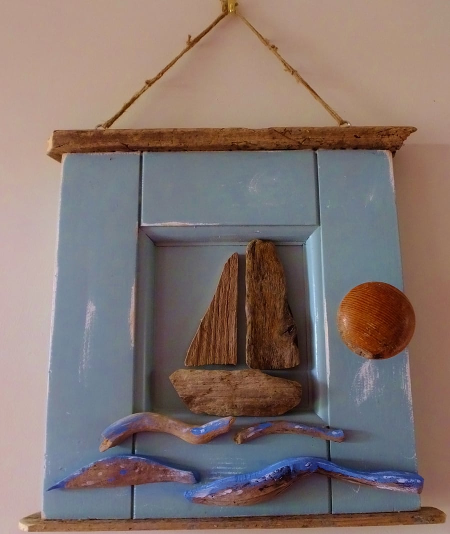 Sailing boat or dinghy mounted in a reclaimed door panel with driftwood waves 