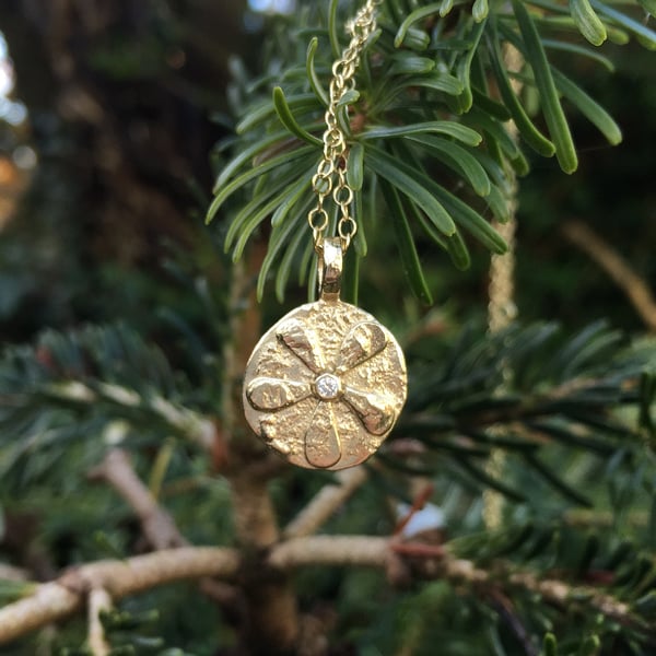 Gold flower pendant with a diamond centre on a gold chain