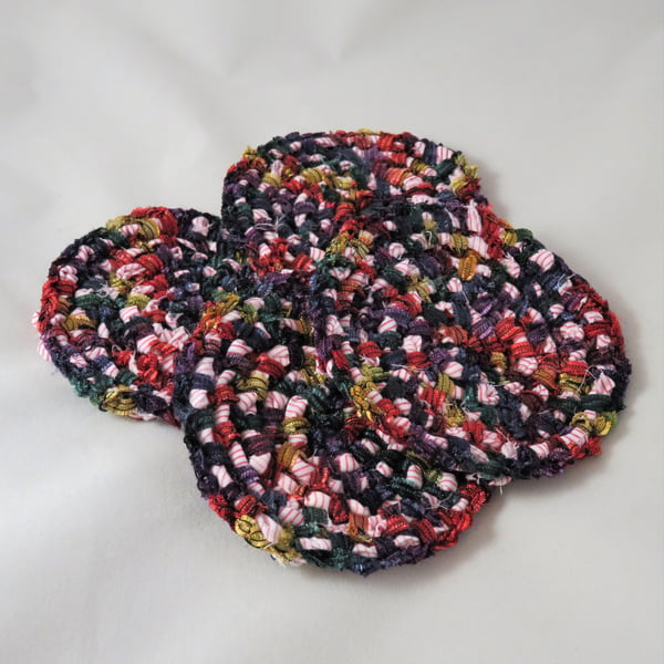 Four crocheted coasters incorporating recycled shirt fabric