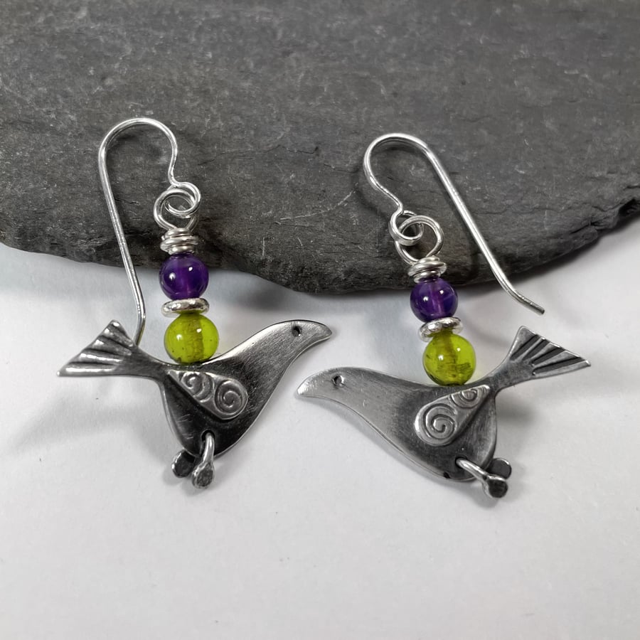 silver bird earrings with purple and green beads.