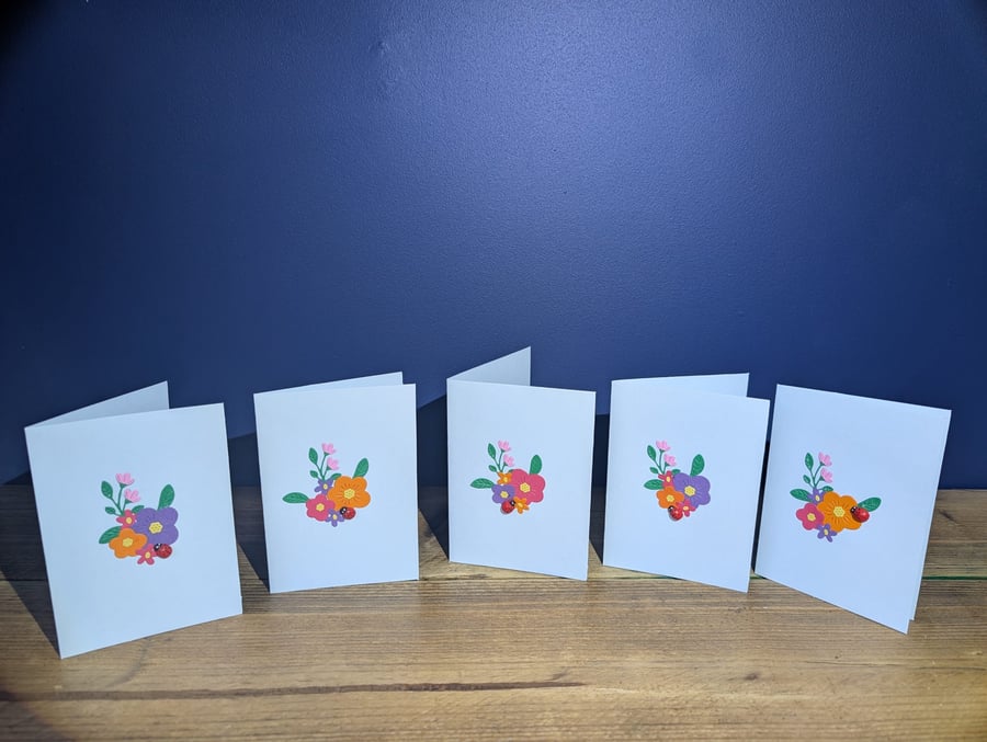 Five blank blue cards with handmade floral design with ladybird inc. envelopes