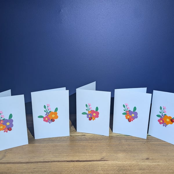 Five blank blue cards with handmade floral design with ladybird inc. envelopes