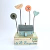Little wooden painted house with buttons, flower and clay heart garden