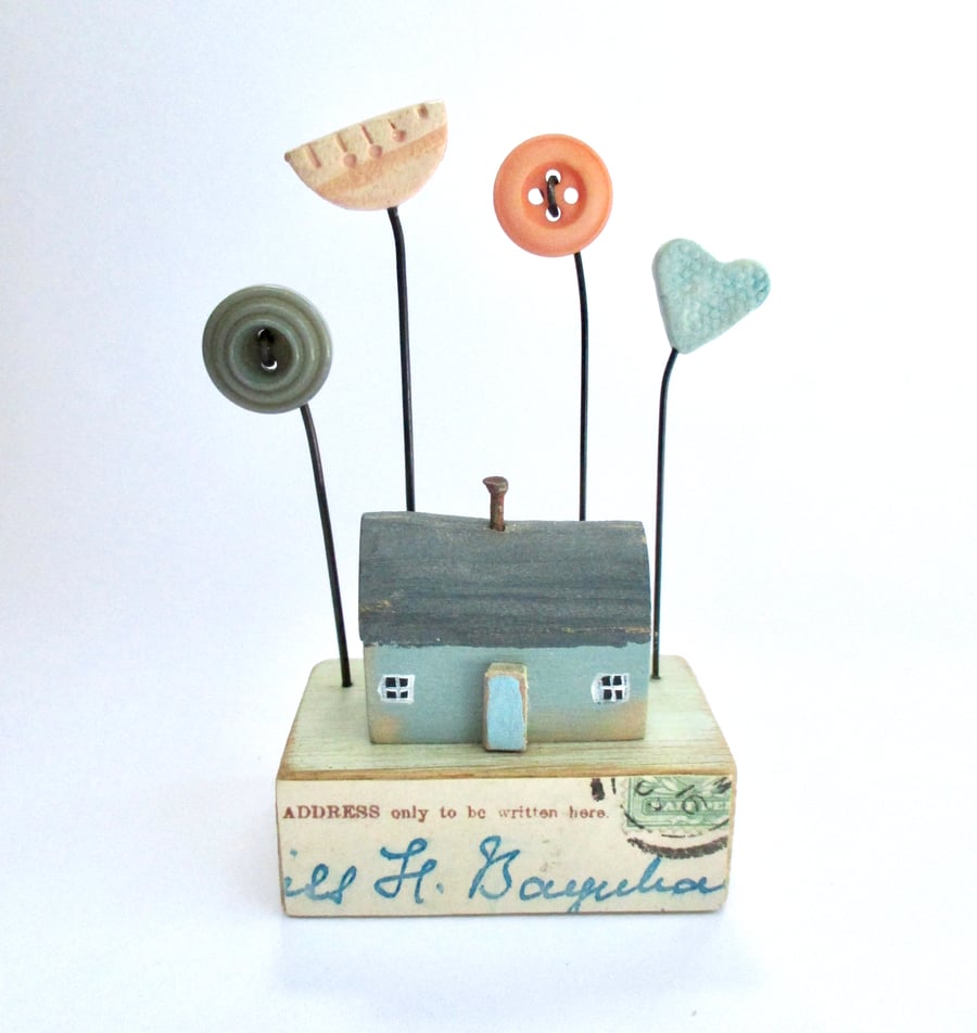 Little wooden painted house with buttons, flower and clay heart garden
