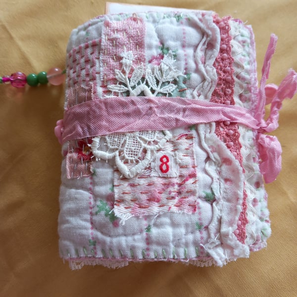 The pink and white needlecase, with pockets, pins, needles and  samples