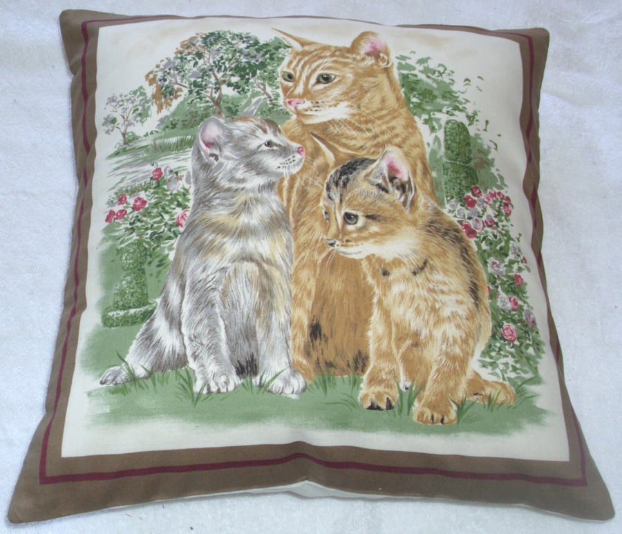a lovely ginger cat and her two kittens in the garden cushion
