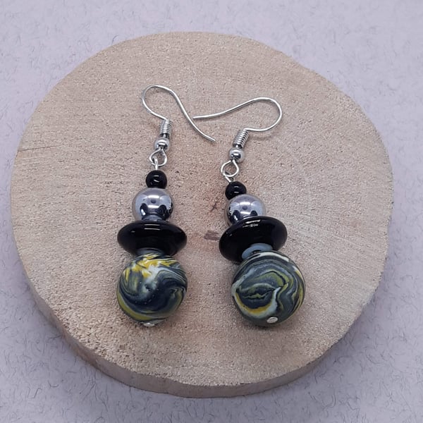 Dangly earrings in a yellow and black swirl design