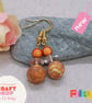 Polymer clay earrings in an orange, yellow, sienna and cream unique swirl design