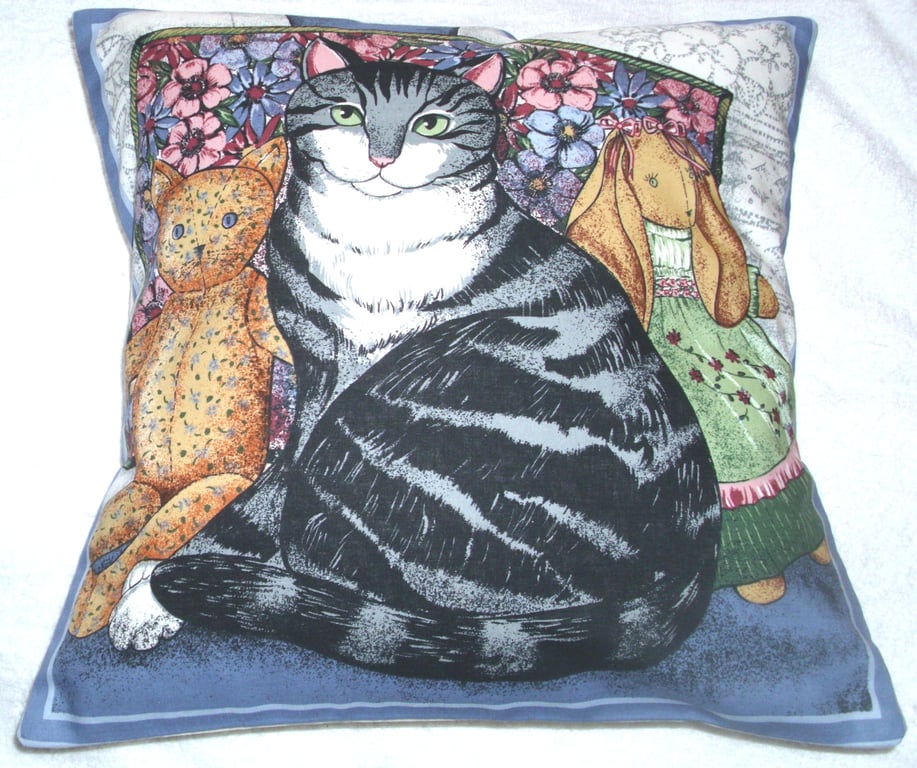 A very pretty grey and white Tabby cat with her toys cushion