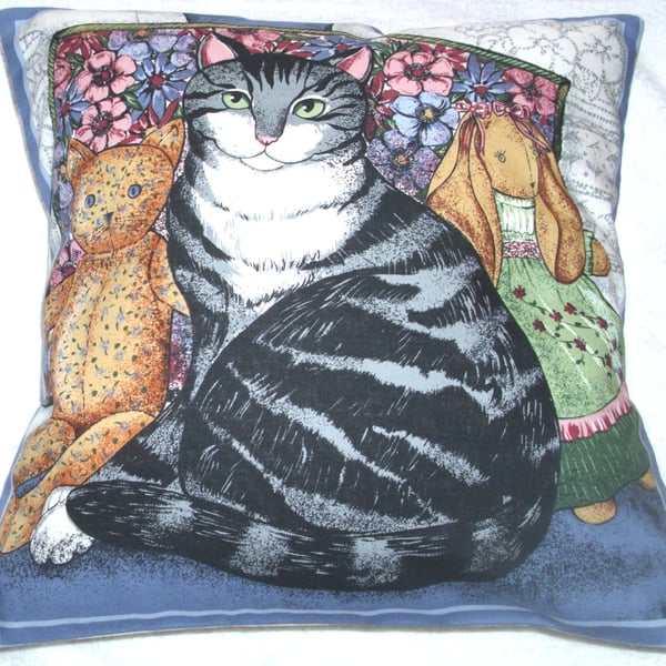 A very pretty grey and white Tabby cat with her toys cushion