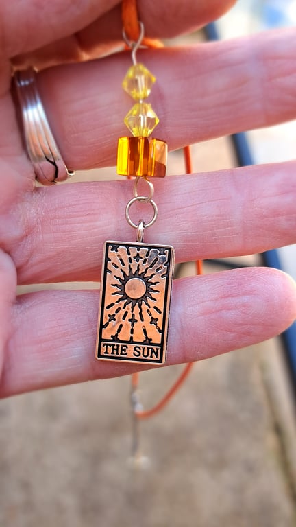 The Sun tarot pendant on an orange rope necklace