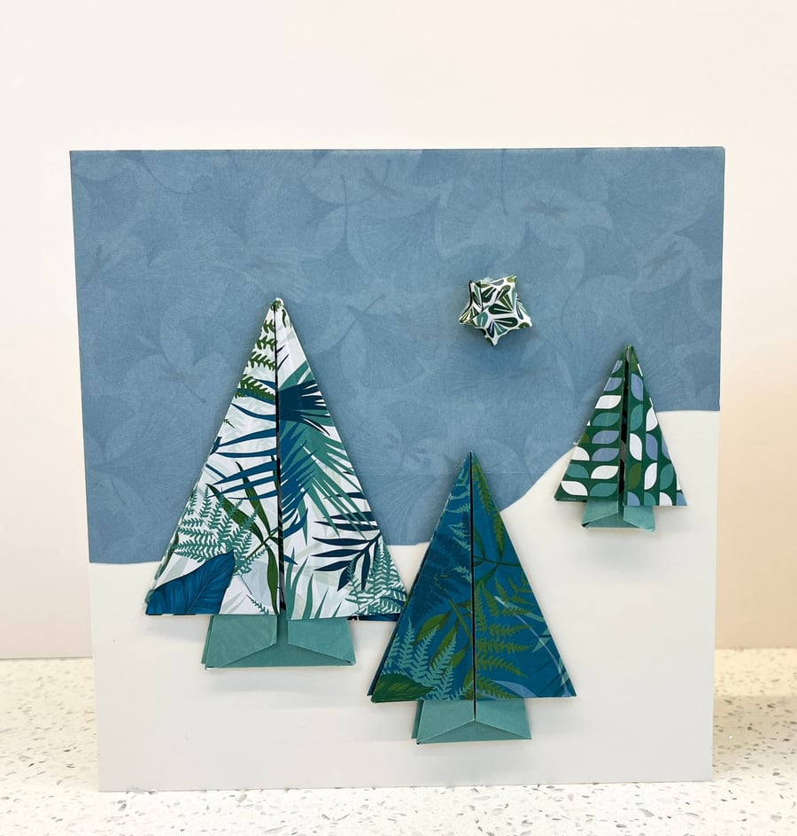 Christmas cards featuring festive origami trees in a snowy landscape. 