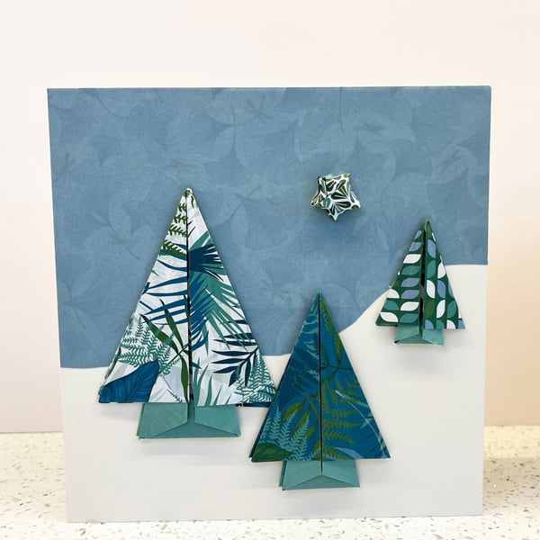 Christmas cards featuring festive origami trees in a snowy landscape. 