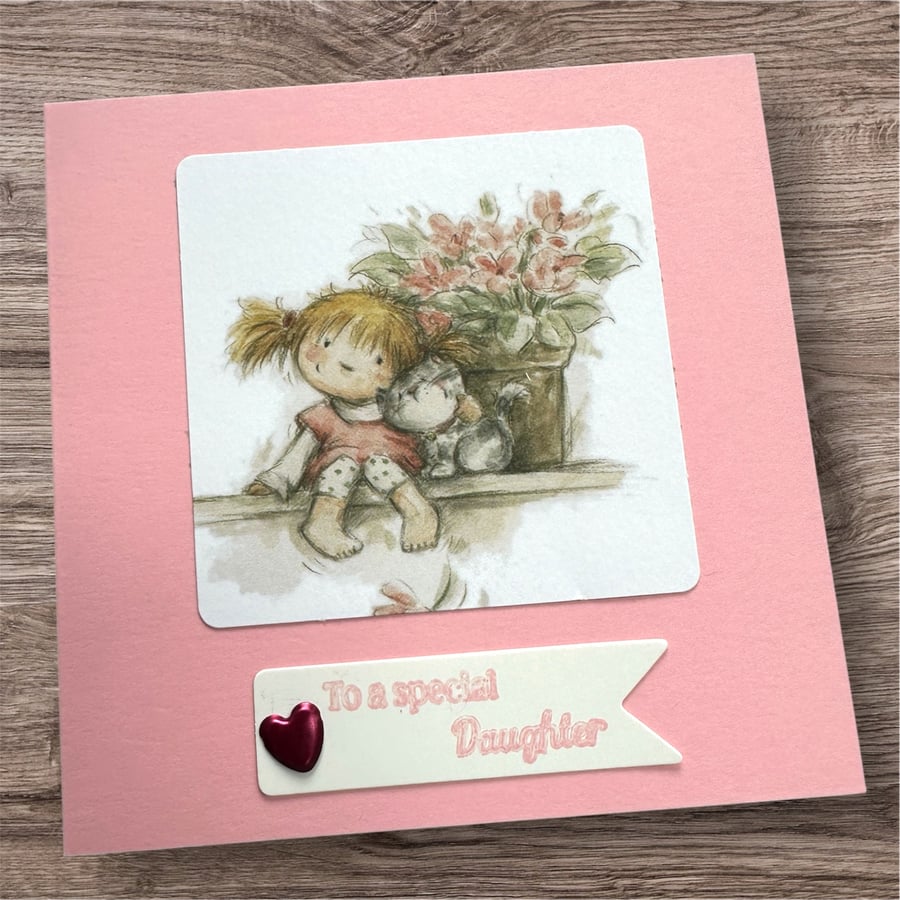 Birthday card for a special daughter.  Cute girl sat with her cat and flowers 