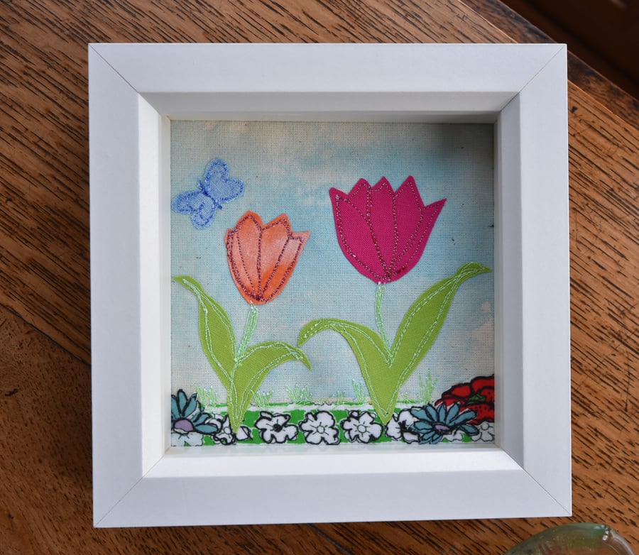 Box framed small applique of tulips on blue colourwash background.