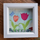 Box framed small applique of tulips on blue colourwash background.