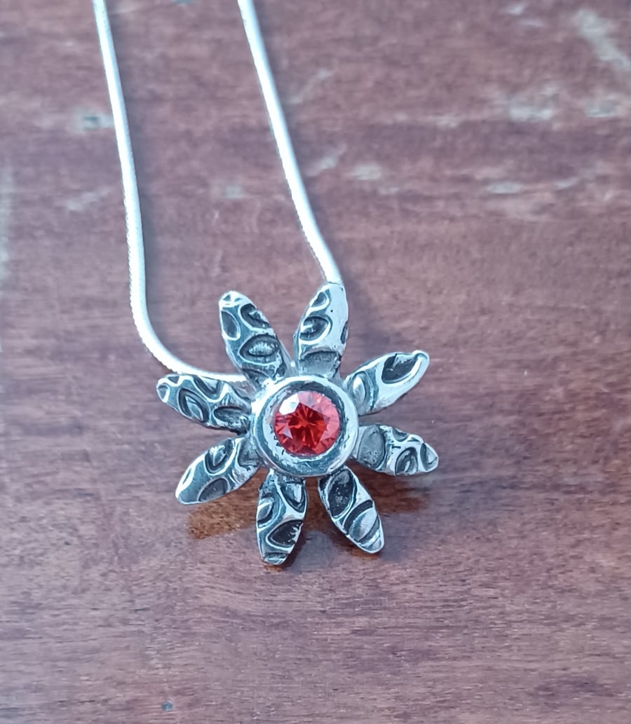Silver daisy pendant with a red centre 