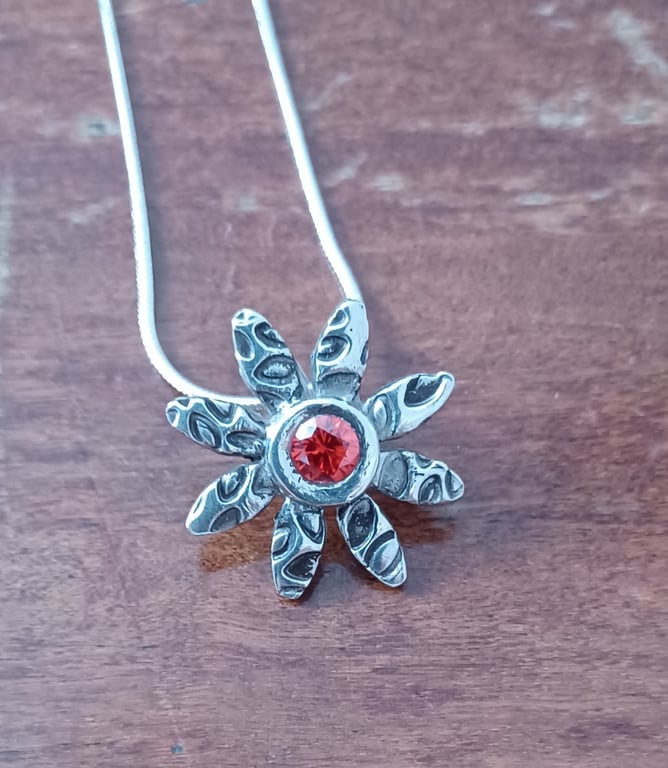 Silver daisy pendant with a red centre 