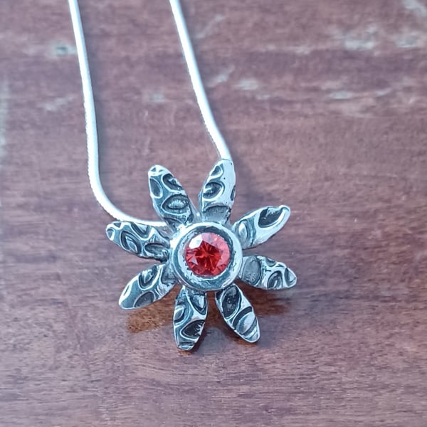 Silver daisy pendant with a red centre 