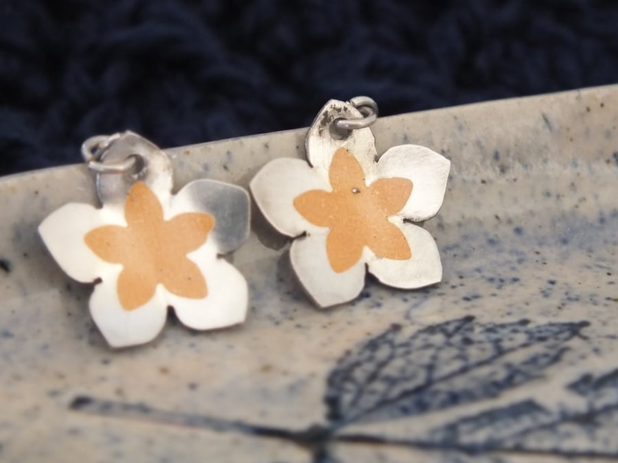 Flower shaped silver earrings with amber coloured detail