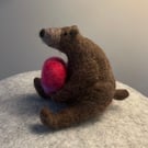 Needle felted bear holding a pink needle felted heart.