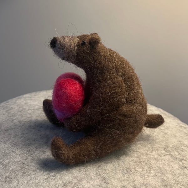 Needle felted bear holding a pink needle felted heart.