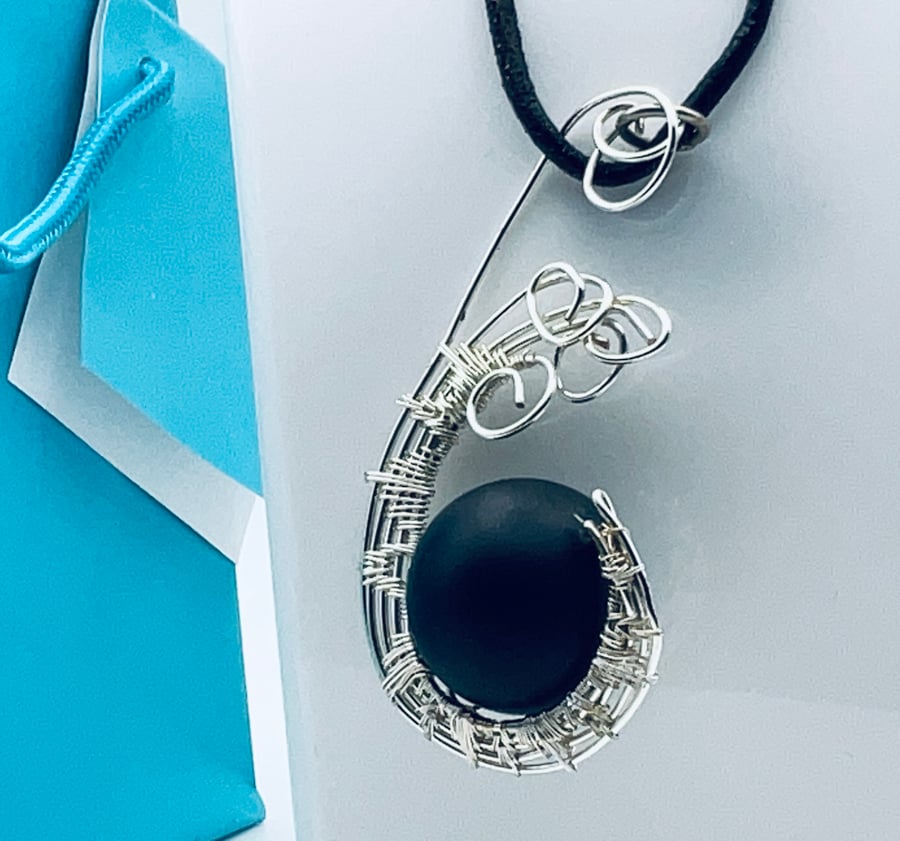 Gorgeous matte black onyx sphere suspended in a silver wire woven twist pendant