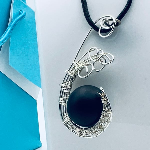 Gorgeous matte black onyx sphere suspended in a silver wire woven twist pendant