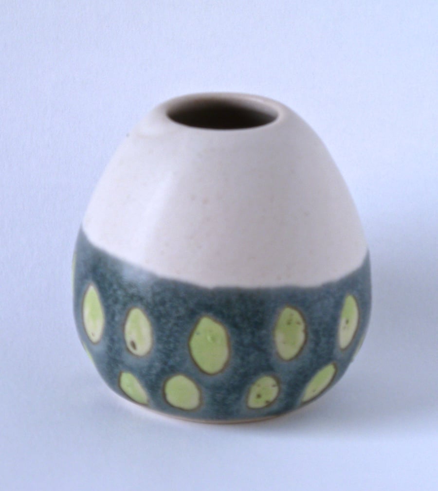 A hand thrown and decorated bud vase .