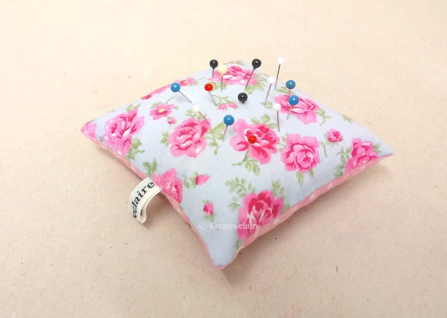 Pin cushion in blue with pink flowers, pink with white spots on the reverse.