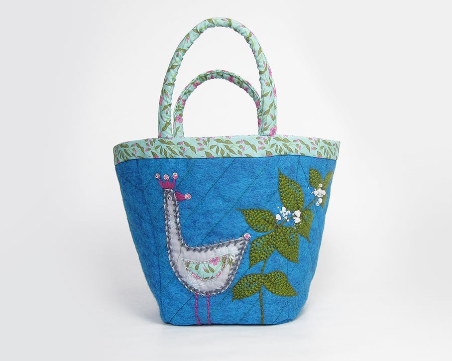 Turquoise project bag with appliquéd bird and dead nettle embroidery