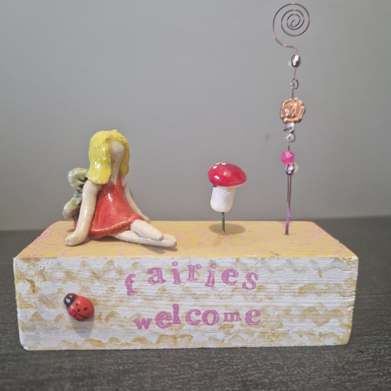 Fairies Welcome printed on a wooden block with ceramic fairy