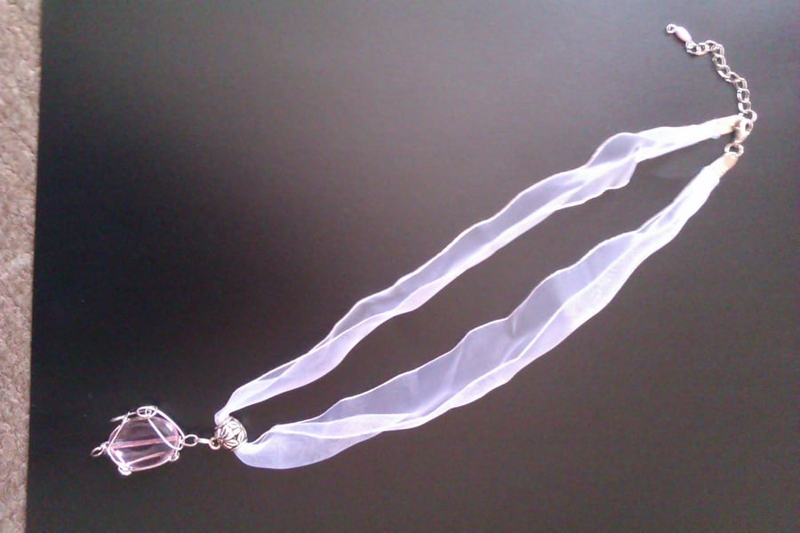 Wire wrapped pink oval pendant on white ribbon necklace.