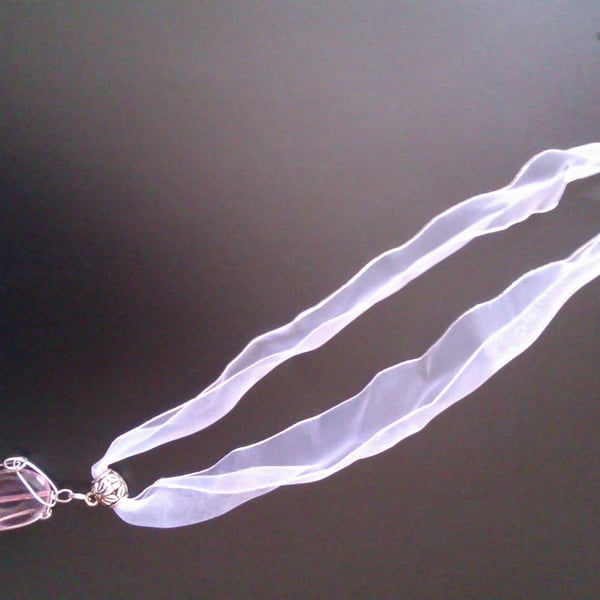 Wire wrapped pink oval pendant on white ribbon necklace.