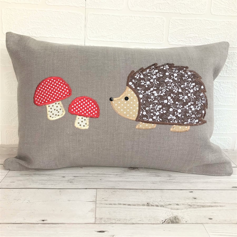 Hedgehog cushion in taupe with brown hedgehog and red toadstools