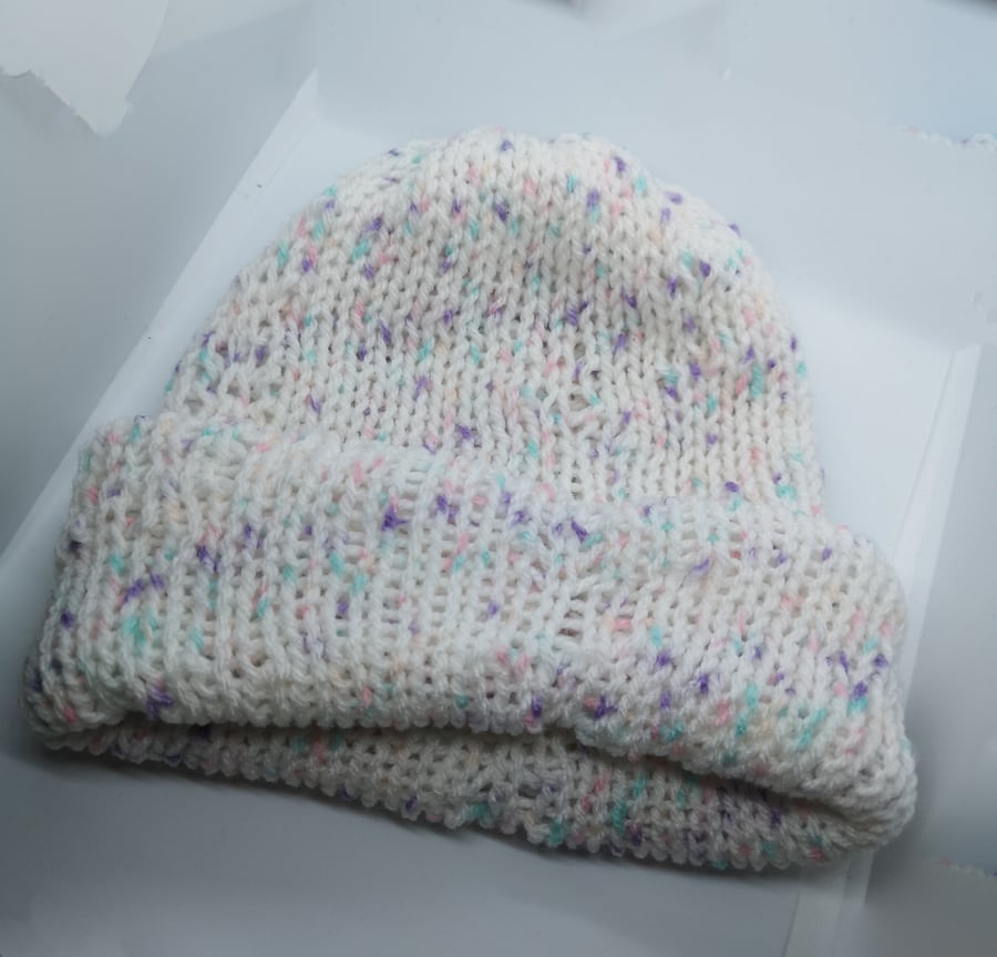 Handknitted white hat with flecks of purple and pink