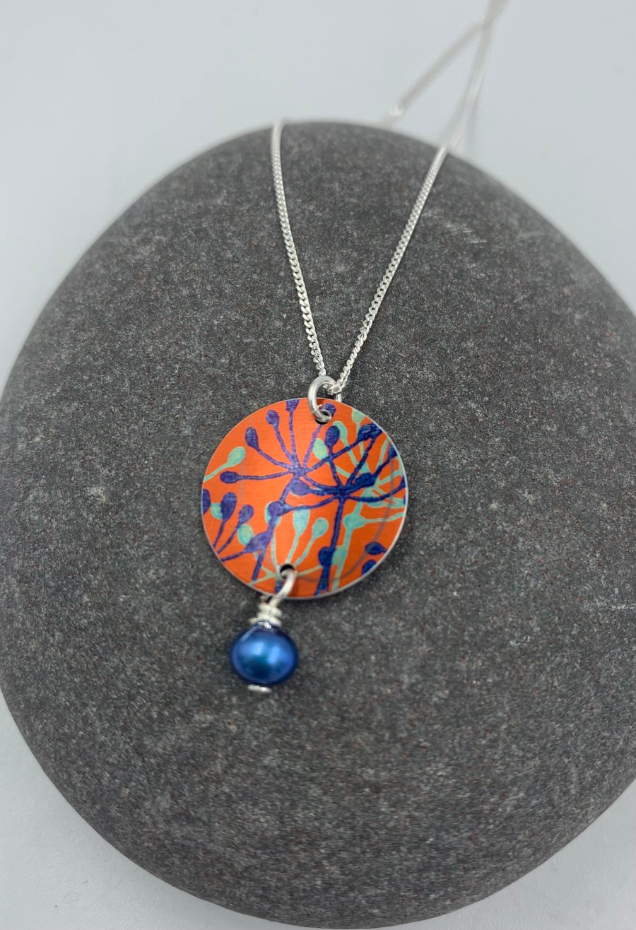 Orange and blue aluminium cow parsley circle pendant with pearl 