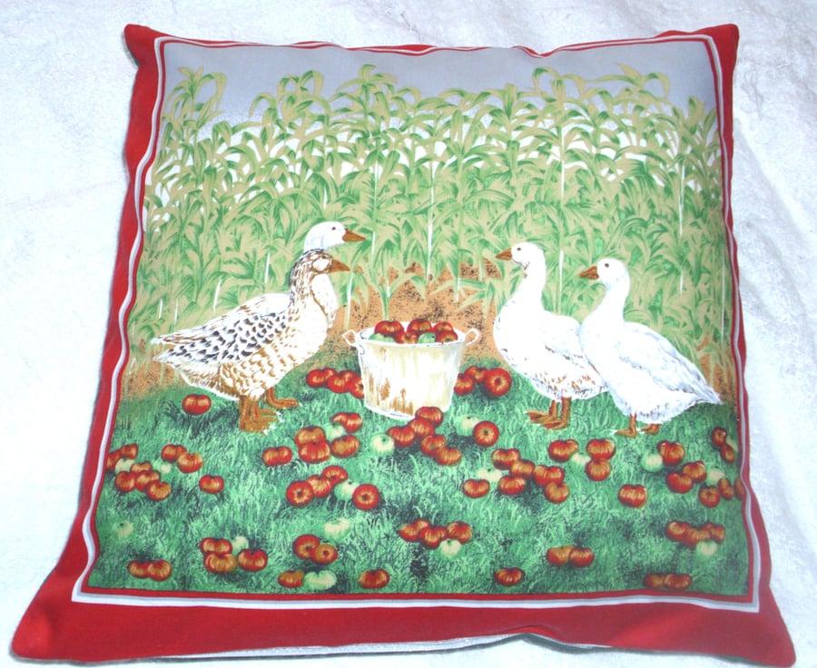 four geese in a corn field with lovely red apples in a pail cushion