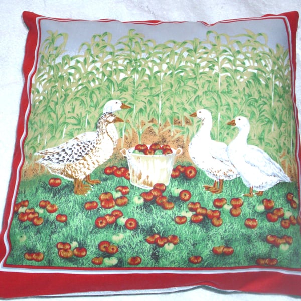 four geese in a corn field with lovely red apples in a pail cushion