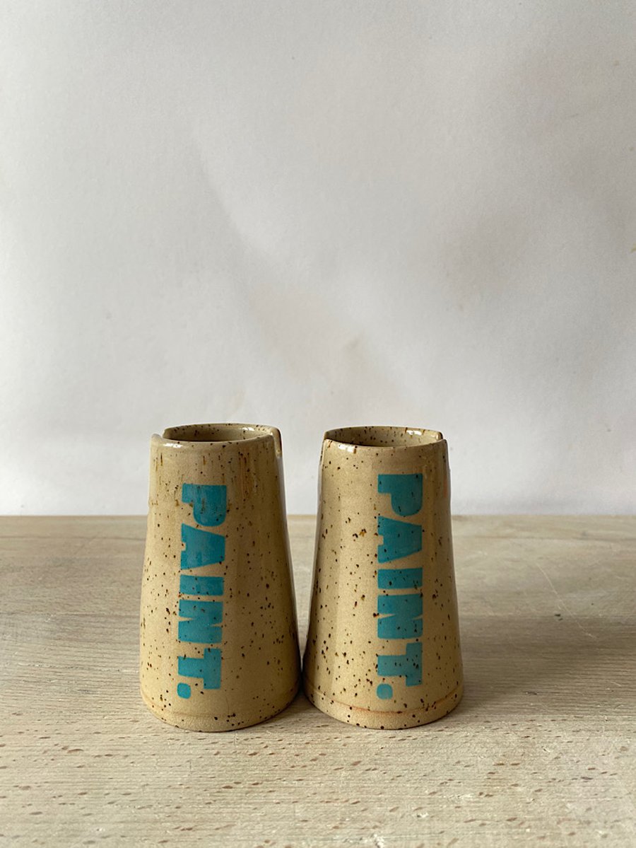 Ceramic paint pot with brush grooves.