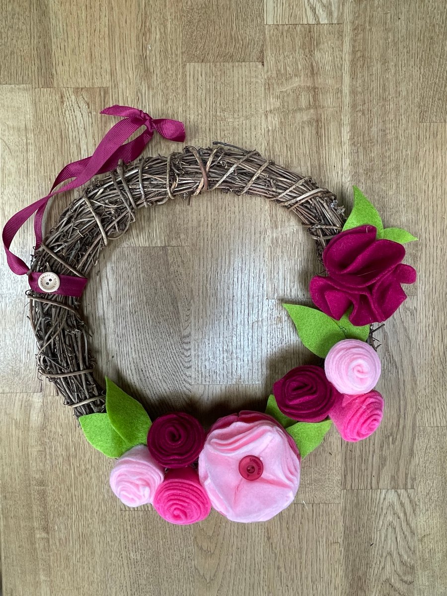 Round rattan wreath with vibrant pink felt flowers