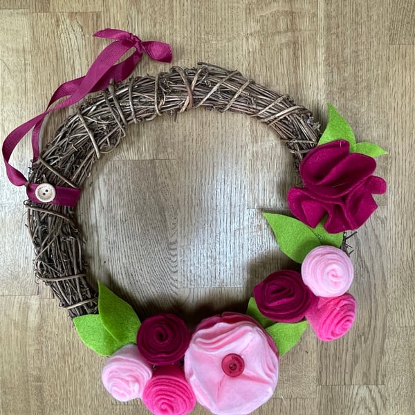 Round rattan wreath with vibrant pink felt flowers
