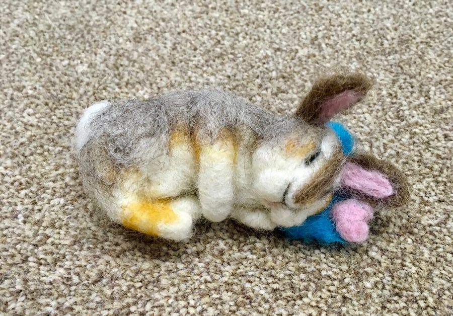 Needle felt rabbit sleeping on little blue cushion 