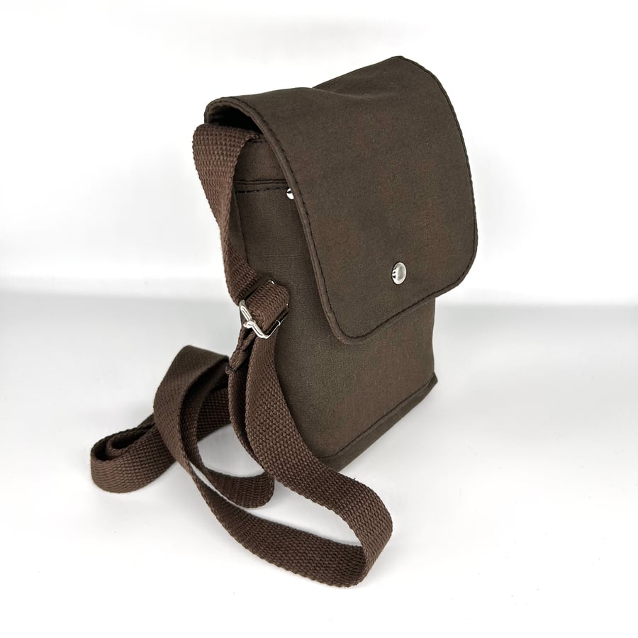 Cross body bag in brown durable fabric with adjustable webbing strap. 