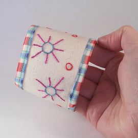 Textile cuff in cotton with button fastening and embroidered suns